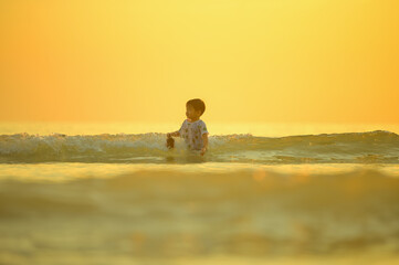 Asian boy playing on a sandy beach near the sea.
