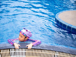 Asian child or kid girl wearing swimming suit to learning on swimming pool , learn and training...