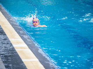 Asian child or kid girl wearing swimming suit to learning on swimming pool , learn and training...