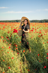 Beautiful brunette woman in a black dress in a poppy field