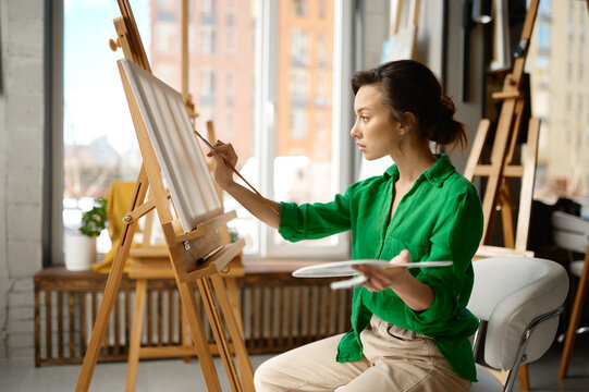 Woman painting brush on canvas at workshop during art lesson class