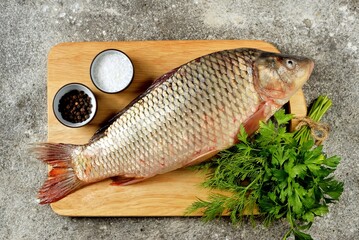 Fresh raw river carp on a cutting board with parsley, sea salt and pepper