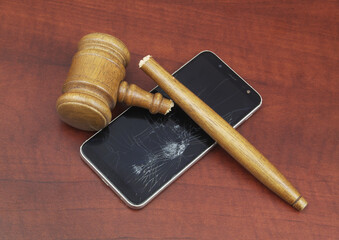 Broken wooden judge gavel and  damaged phone on table close-up. 