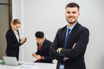 Portrait of business owner or young businessman smiling looking at camera. In meeting room. Handsome businessman manager smiling confidently standing in office at team meeting.