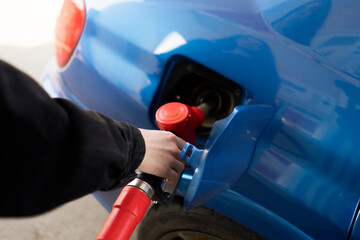 young girl is refueling the blue car on a gas station