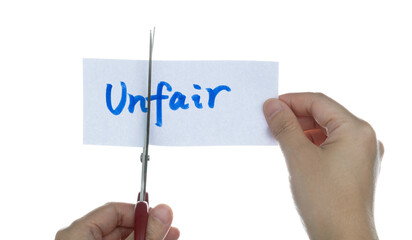 Scissors cutting word unfair on paper