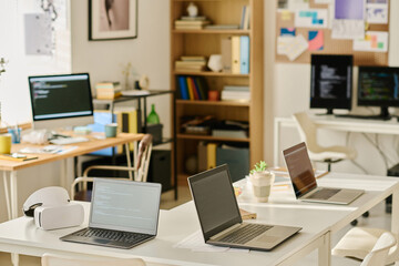 Horizontal image of modern IT office with computers on workplaces of programmers