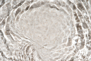 The texture of water on a sand background in bright sunlight.