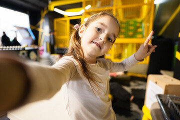 Preschooler girl making selfie at children play center.