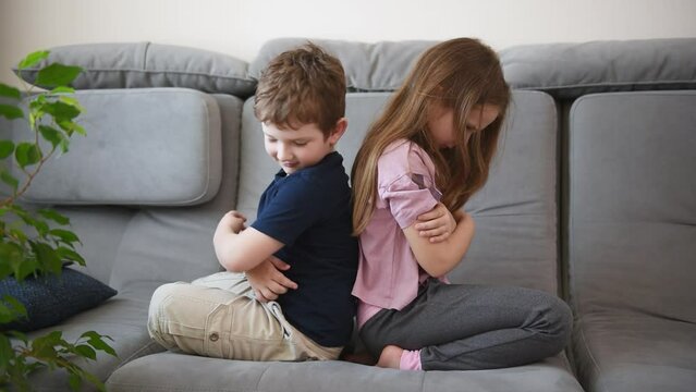 offended brothers and sisters sit back to back on the couch. children's emotions