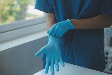 Doctor or nurse putting on blue nitrile surgical gloves, professional medical safety and hygiene...