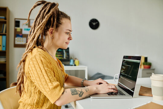 Young professional developer working with codes on laptop sitting at her workplace in office
