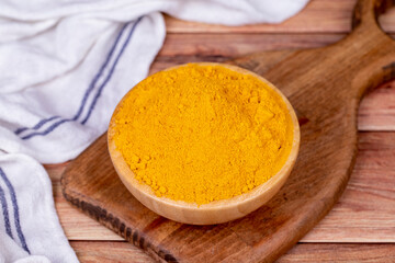 Powdered turmeric on wooden background. Dried ground turmeric powder spices in wooden bowl