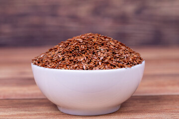 Linseed on wooden background. Flax seed or Flax seed in ceramic bowl
