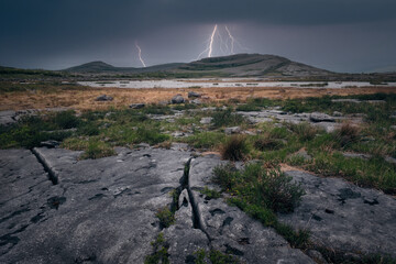 Dramatic cloudy lakeside landscape scenery with thunderstorm and lightning strikes over mountains...
