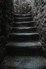 A mysterious staircase winding up a dark wall. Light filters from top of image.