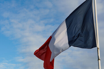 Straight on view of a waving French flag against a bright blue sky.