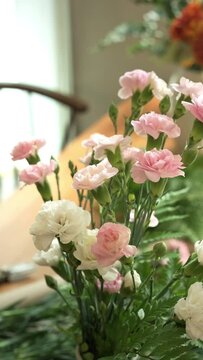 Beautiful pink rose and carnation bouquet in a vase on wooden table in cozy living room