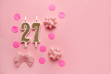 Number 27 on pastel pink background with festive decor. Happy birthday candles. The concept of celebrating a birthday, anniversary, important date, holiday. Copy space. Banner