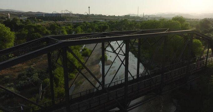 Bicyclists riding across the Iron Horse pedestrian bridge in Santa Clarita, California with Six Flags Magic Mountain in the background in the late afternoon on a sunny day.
