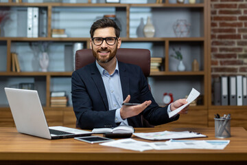 Portrait of mature businessman inside office at workplace, man with documents smiling and looking...