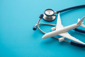 Airplane and stethoscope on blue background with copy space. Going abroad for medical care. Medical...