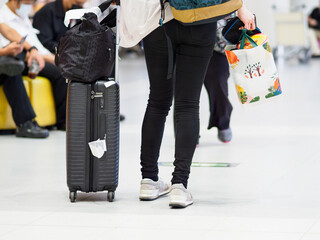 空港のロビーでスーツケースを持って歩く女性の後ろ姿