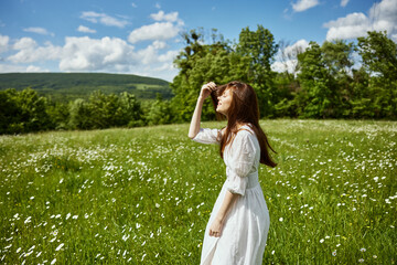 Obraz premium portrait of a woman in a light dress in a chamomile field turning her face away from the camera