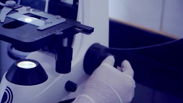 Zoom out revealing a female scientist looking a sample under the microscope in the laboratory