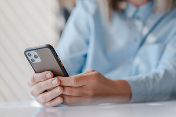 Closeup business woman hands holding mobile phone reading text message, communication online, ordering food sitting in modern office. Female shopping online with sales, mobile banking. Technology