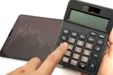 hand pushing the calculator for the trend of the stock that suitable for buy or sell. Financial accounting stock market graphs analysis