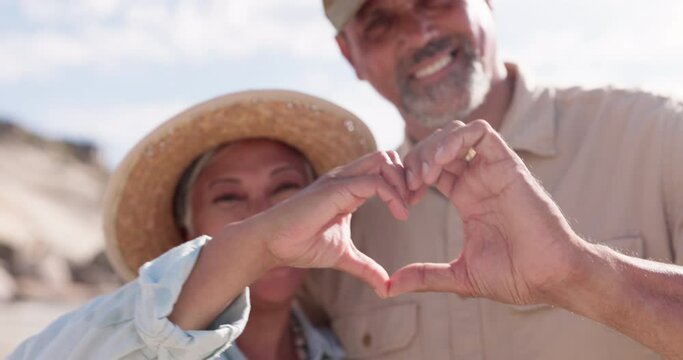 Senior couple portrait, heart and hand sign for love on the beach with happy marriage. Ocean, sea and smile of elderly people together with loving and kindness hands gesture in nature with happiness