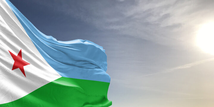 Djibouti national flag cloth fabric waving on beautiful grey sky Background. - Powered by Adobe