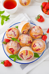 Homemade strawberry muffins or cupcakes on a plate on a white wooden background. Selective focus. Close up.