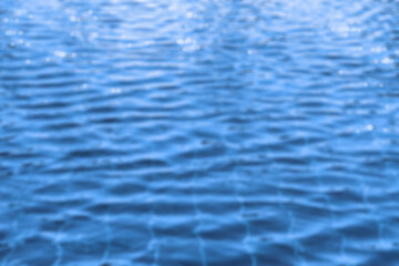 Blurry image of clear water ripple in blue swimming pool. Background for inspiration idea or template.