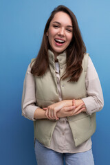 smiling pleasant european brunette young lady in vest and shirt on studio background