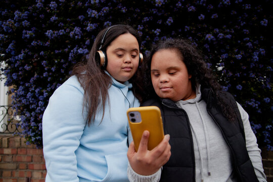 Two plus-sized women with Down Syndrome watching a video on a phone