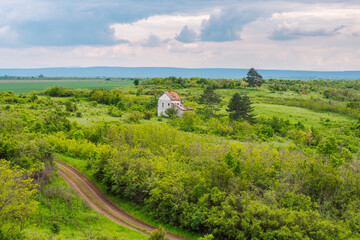 View of panoramic rural landscape with bushes, shrubs, trees and abandoned house. Picturesque spring landscape from northern Bulgaria.