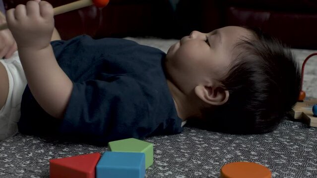 Adorable 8 Month Old Baby Getting Nappy Changed As He Lays On The Floor Whilst Sticking Toy In Mouth. Low Angle, Locked Off