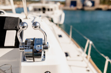 Metal control levers on panel of contemporary catamaran moored in sea bay on sunny day