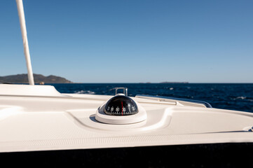 Compass on white panel of contemporary catamaran sailing in sea on sunny day