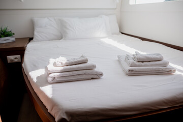 Interior of bedroom in cabin of catamaran with comfortable bed with white bedclothes