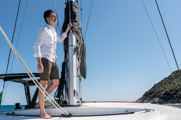 Side view of male standing with rope near mast on sailing catamaran in sea