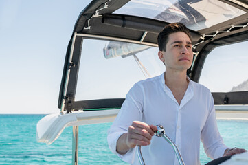 Male standing at control panel and sailing modern catamaran in sea in summer looking away
