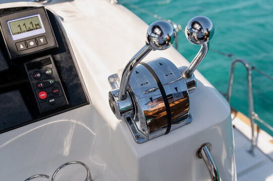 Metal control levers on panel of contemporary catamaran moored in sea bay on sunny day