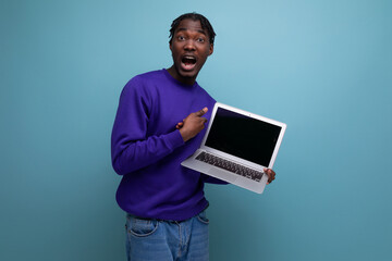surprised american young brunette man with dreadlocks with laptop