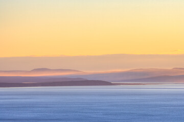 Morning seascape. View of the sea bay and hilly coast. Beautiful dawn landscape. Nature of Siberia and the Russian Far East. Travel, tourism and hiking in the Magadan region. Sea of Okhotsk, Russia.