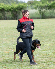 woman and rottweiler in nature - obrazy, fototapety, plakaty