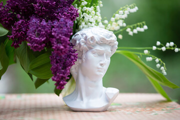 Lilac branches lie with the head of Michelangelo. The concept of creativity and art.