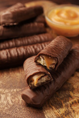 Sweet tasty chocolate bars with caramel on wooden table, closeup
